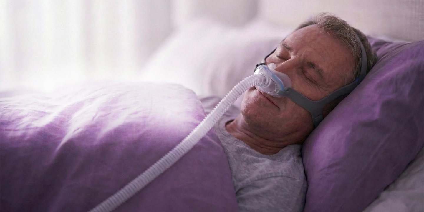Un uomo dorme indossando una leggera maschera CPAP